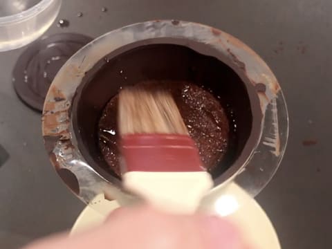 Punchage du biscuit chocolat qui se trouve dans le cône en chocolat, à l'aide d'un pinceau pâtissier