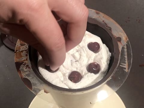 Des cerises à l'eau de vie sont piquées dans la Chantilly dans le cône en chocolat