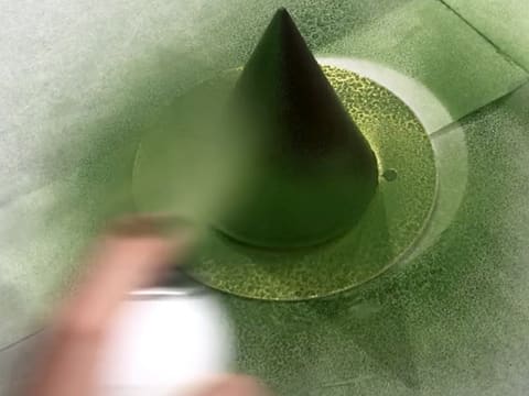 Pulvérisation d'un spray effet velours vert sur le cône en chocolat