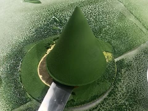 Le cône en chocolat vert est pris avec une spatule coudée