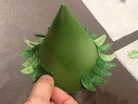 Des feuilles en chocolat vert sont collées sur les gouttes de chocolat vert sur le sapin en chocolat