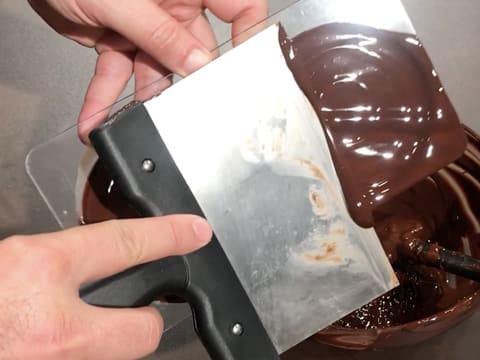 Le moule qui sert de base au cône est raclé avec une spatule pour retirer l'excédent de chocolat fondu