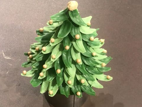 Le sapin en chocolat vert est décoré avec les perles croustillantes dorées