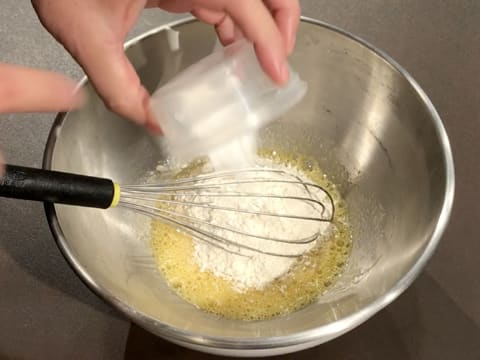 Ajout de la levure chimique dans la préparation à base d'œufs et de sucre en poudre