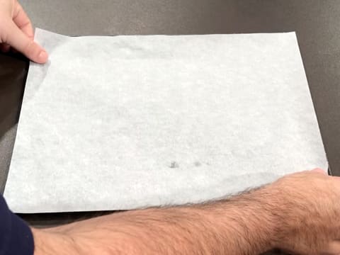 Une feuille de papier sulfurisé est placée sur la plaque à pâtisserie graissée