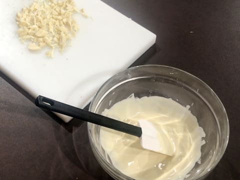 Un bol de chocolat blanc fondu et du chocolat blanc haché sont sur le plan de travail