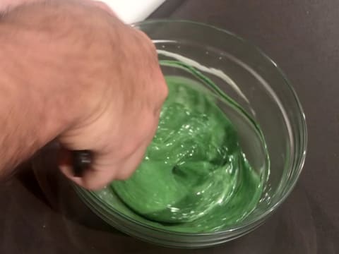 Mélange à la spatule maryse du chocolat blanc fondu avec le colorant vert