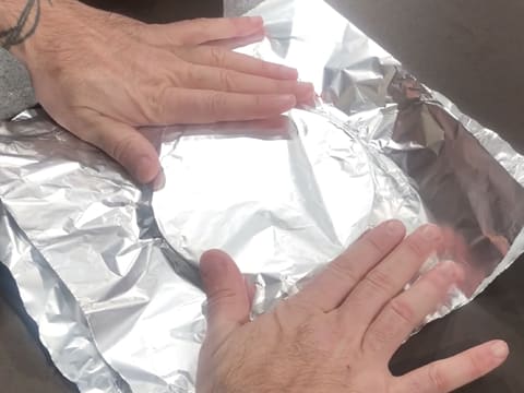 Les deux feuilles de papier aluminium superposées l'une sur l'autre sont placées sur le fond du moule, le tout posé sur le plan de travail