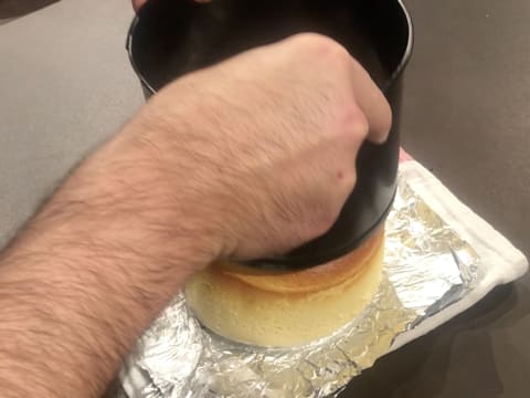 Le moule à charnière à fond amovible est glissé vers le haut et retiré de son fond et du cheesecake