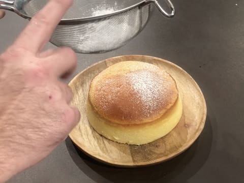 La surface du cheesecake japonais extra léger est saupoudrée d'un léger voile de sucre glace qui est tamisé dans la passoire fine