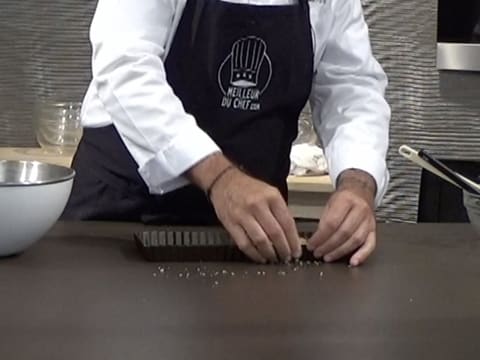 La pâte Muesli est étalée et aplatie du bout des doigts au fond du moule à tarte cannelé et rectangulaire