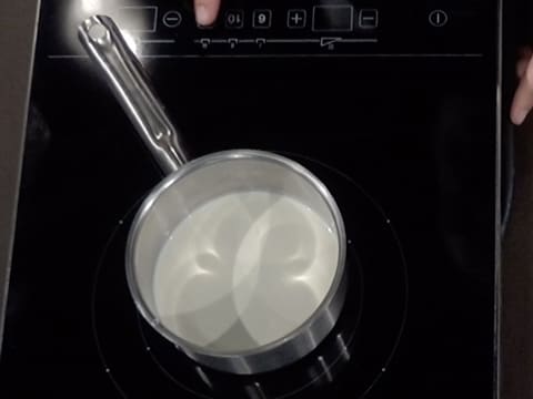 La casserole qui contient la crème fleurette et le sirop de glucose est placée sur une plaque de cuisson