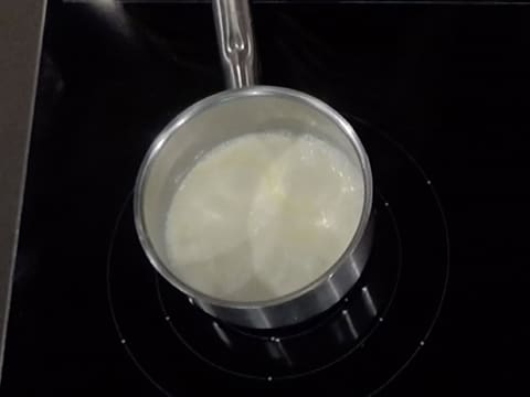 La crème fleurette commence à entrer en ébullition dans la casserole qui est posée sur la plaque de cuisson