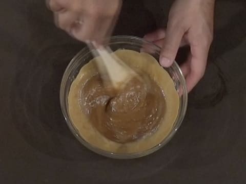 À l'aide de la spatule, mélange du chocolat blond Dulcey fondu et de la crème par le centre