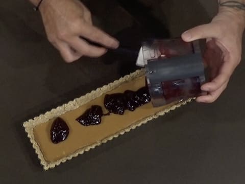 Le confit à la myrtille est versé sur la ganache Dulcey qui recouvre le biscuit Muesli qui est dans le moule à tarte cannelé et rectangulaire