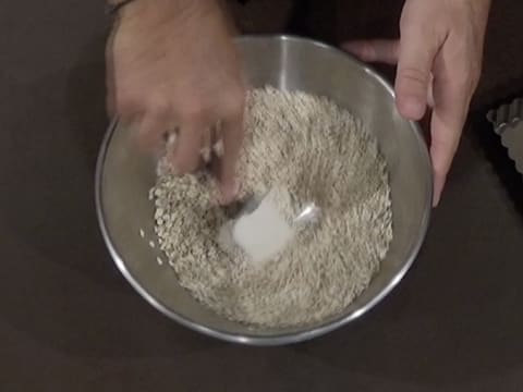 Mélange des flocons d'avoine et de la fleur de sel dans le cul de poule, à l'aide d'une spatule type maryse