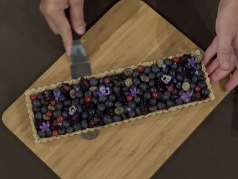 La lame d'une grande spatule métallique coudée est passée sous la tarte, entre la pâte Muesli et le fond du moule