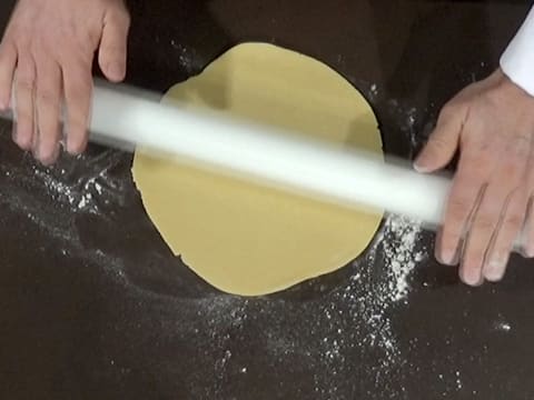 À l'aide d'un rouleau à pâtisserie, la pâte sablée est abaissée en forme de rond sur le plan de travail fariné