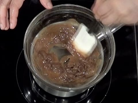 Mélange et fonte du beurre de cacao Mycryo et du chocolat au lait avec la spatule maryse dans le saladier qui est placé sur un bain-marie