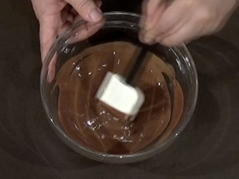 Mélange de la préparation chocolatée et pralinée avec la spatule maryse, dans le saladier placé sur le plan de travail