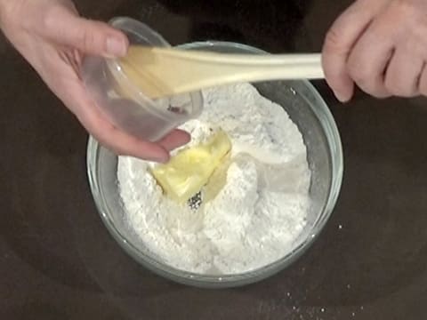 Ajout du beurre pommade et du sel fin sur le mélange farine et sucre glace dans le saladier