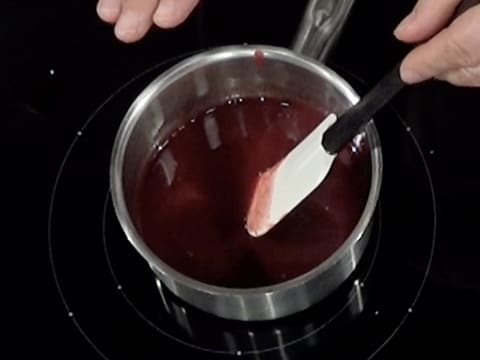 La préparation aux fruits rouges est en train de cuire dans la casserole tout en étant mélangée avec la spatule maryse
