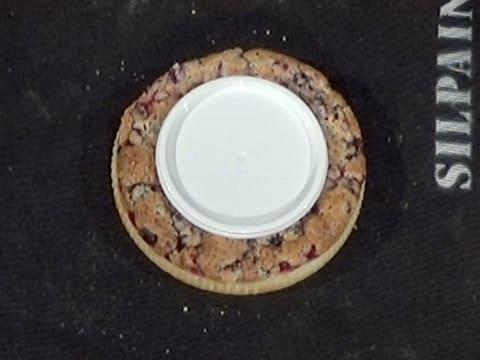 Un couvercle est posé au centre de la tarte qui se trouve sur la toile de cuisson en silicone