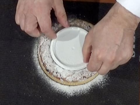 Le couvercle qui est posé au centre de la tarte saupoudrée de sucre glace, est retiré