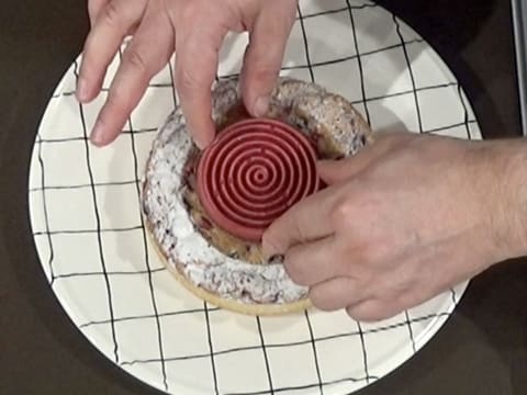 Le tourbillon de gelée de fruits rouges est déposé au centre de la tarte sur le disque de croustillant praliné