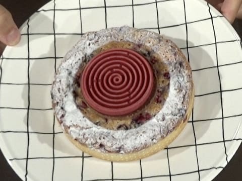 Obtention de la tarte de fruits rouges décorée au centre avec le tourbillon de gelée de fruits rouges et décorée de sucre glace sur tout le pourtour