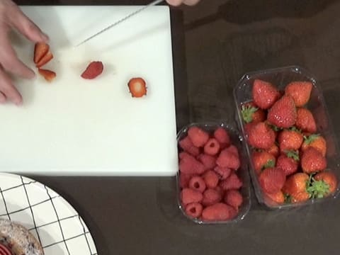 Des fraises et des framboises sont coupées en morceaux à l'aide d'un couteau sur une planche à découper