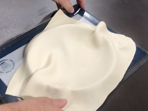 Le rectangle de pâte feuilletée est posé sur le cercle à tarte qui se trouve sur la plaque à pâtisserie perforée recouverte d'une toile de cuisson en silicone