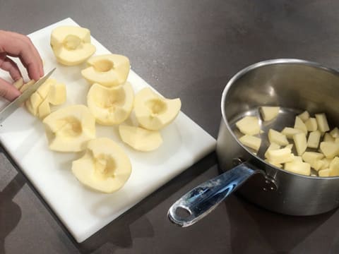 Les pommes sont coupées en morceaux au couteau de cuisine sur une planche à découper