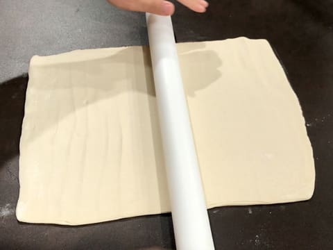 À l'aide d'un rouleau à pâtisserie, la pâte feuilletée est abaissée en un grand rectangle