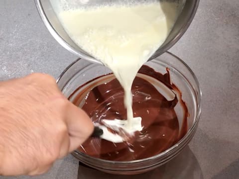 De la crème est versée sur le chocolat fondu dans le saladier