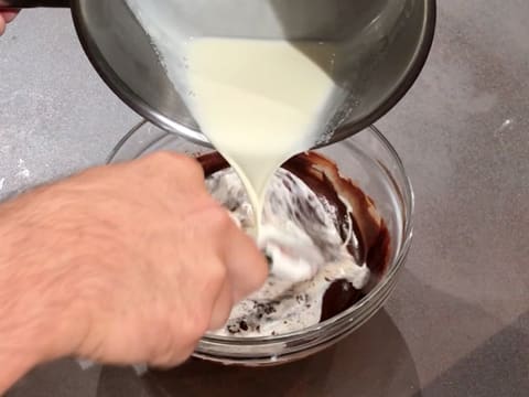 De la crème est versée sur le chocolat fondu dans le saladier