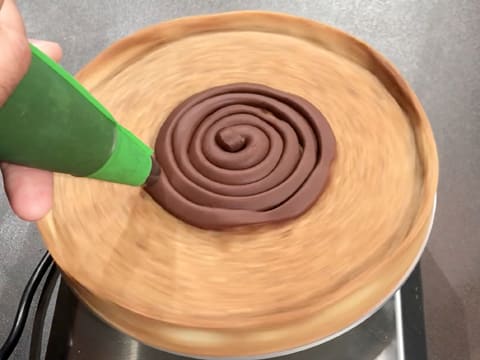 La ganache au chocolat est pochée en spirale sur le fond de tarte cuit