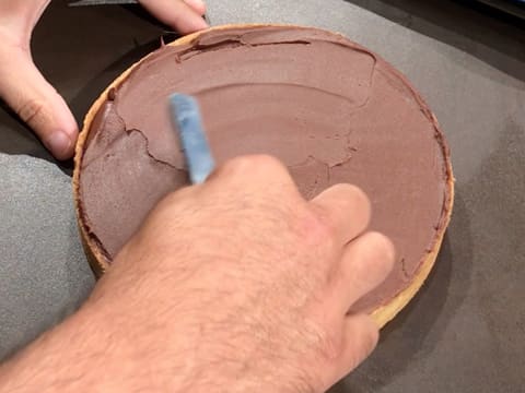 La ganache au chocolat est étalée sur toute la surface du fond de tarte cuit