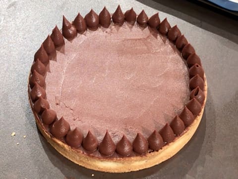 Obtention de la tarte au chocolat qui est décorée avec une rangée de gouttes de ganache au chocolat pochée sur tout le pourtour