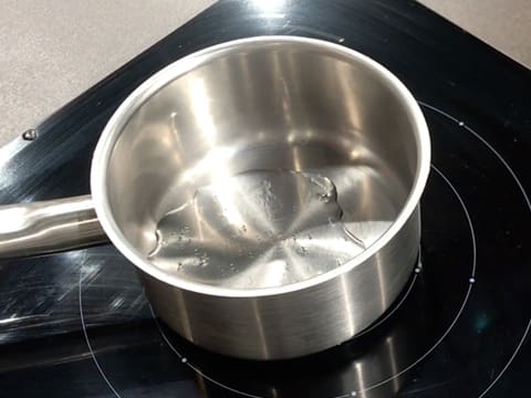 Une casserole contenant du sirop de glucose est placée sur la plaque de cuisson