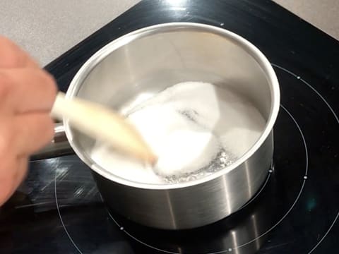 Ajout du sucre en poudre dans la casserole et mélange des ingrédients avec une spatule