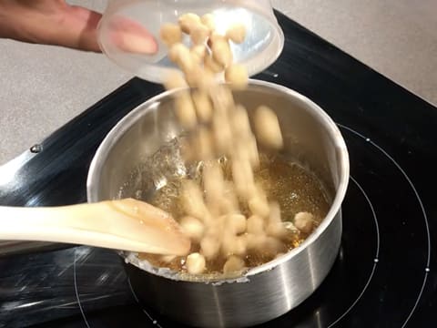 Les noisettes blanchies sont versées sur le caramel dans la casserole