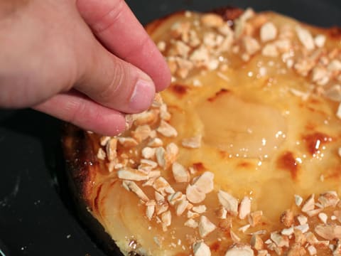 Les noisettes caramélisées concassées sont parsemées sur la tarte aux poires bourdaloue