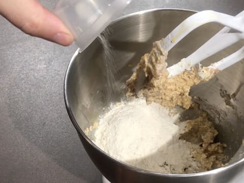 Ajout du sel fin sur la levure chimique, la farine et la pâte dans la cuve du batteur muni de l'accessoire feuille