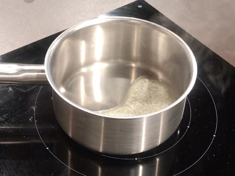 Du beurre est en train de fondre dans une casserole posée sur une plaque de cuisson