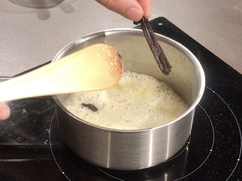 Ajout d'une demi gousse de vanille fendue en deux, dans le beurre et le sucre fondus qui sont en ébullition dans la casserole