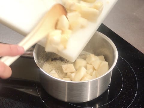 Ajout des morceaux de poires sur le beurre et le sucre fondus qui sont en train de cuire dans la casserole