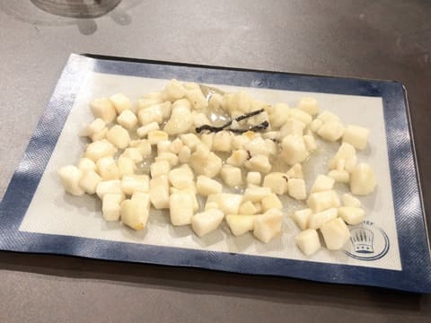 Les morceaux de poires enrobés de beurre et de sucre fondus sont étalés sur la toile en silicone avec la demi gousse de vanille fendue en deux au milieu