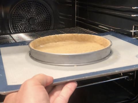 Le fond de pâte dans le cercle à tarte inox est enfourné à mi hauteur sur une plaque à pâtisserie recouverte d'une toile silicone