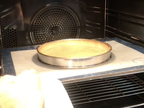 Le fond de pâte est en train de cuire dans le four sur le tapis de cuisson en silicone qui recouvre la plaque à pâtisserie